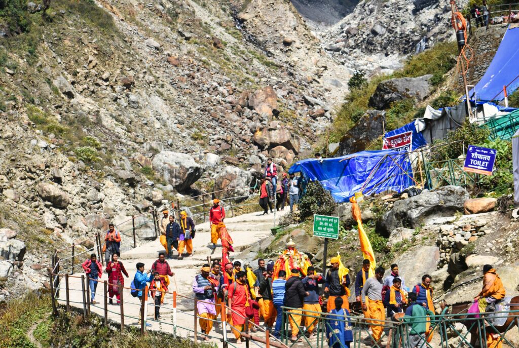 Colorful procession of pilgrims walking along the rocky path in Kedarnath, India.